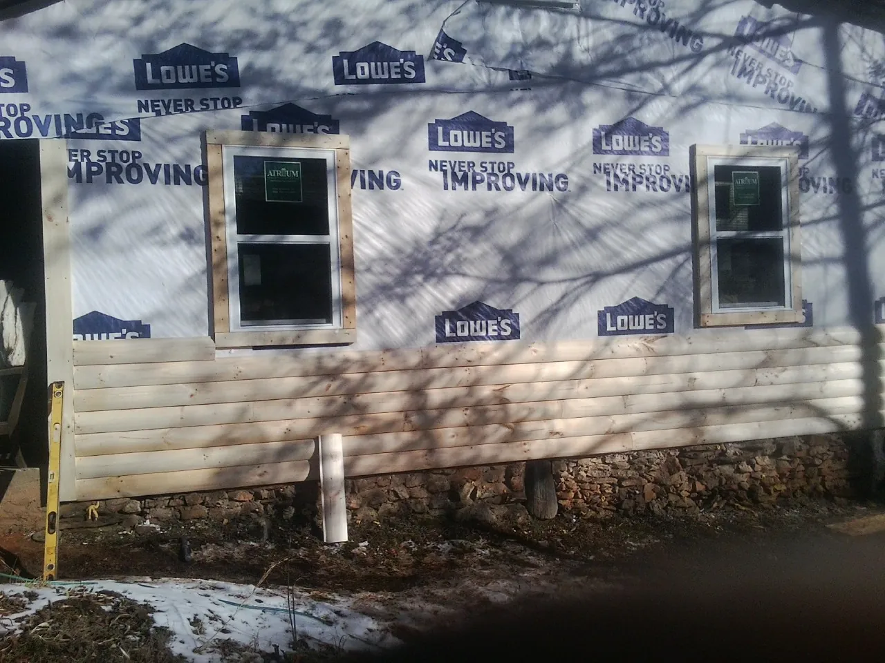 House wrap and new log siding going up on an exterior wall in Medway