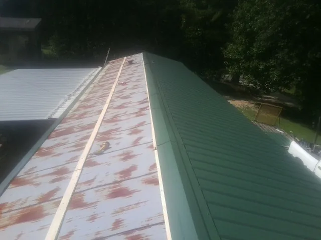 Old rusted panels beside newly installed green metal roofing — Wind Damage Roof Repair by Roofing Brothers in Medway