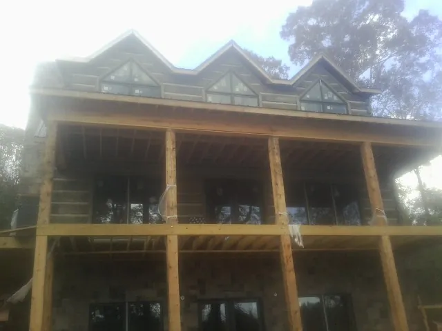 Dormers and porch framing on a large log home under construction — Roof Coating work by our crew in Medway