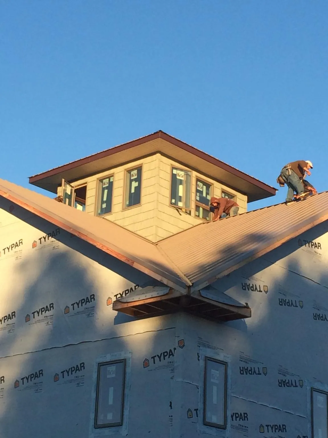 Roofers working around a rooftop cupola on a new metal roof at sunset — Roof Waterproofing in Medway by Roofing Brothers